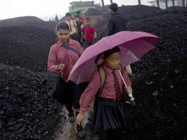 Индийски деца се прибират от училище, минавайки през въглищен склад, в който немалко техни връстници работят