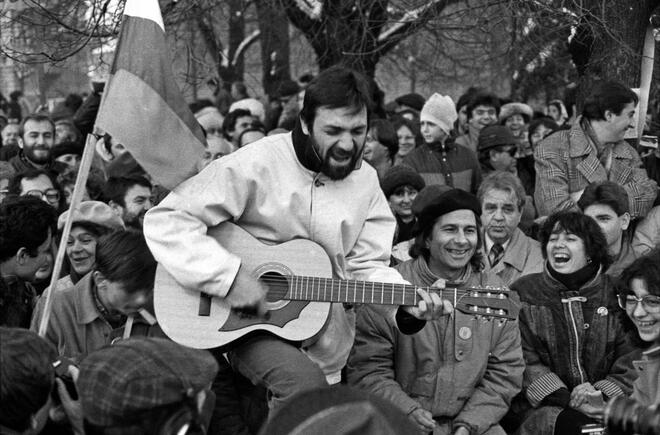 30 декември 1989 г., Пл. "Св. Александър Невски". Новогодишен митинг. Ачо Джендема с изпълнението си предизвиква усмивки у Михаил Неделчев и Пепа Николова