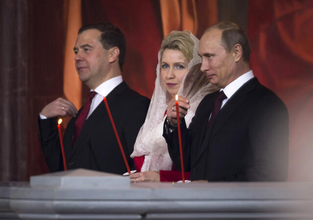 Дмитрий Медведев, съпругата му Светлана и Владимир Путин по време на литургията за Великден