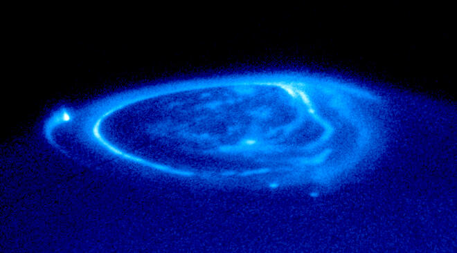 Юпитер, ултравиолетово полярно сияние. Снимката е на Hubble. Ярката ивица вляво, завършваща със светеща точка, са линиите на магнитното поле, протягащо се от атмосферата на планетата към нейния спътник Ганимед.